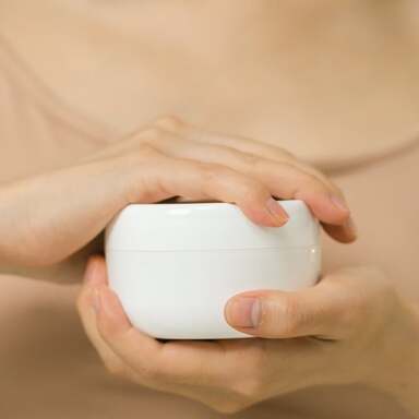 Mujer sosteniendo una crema sin etiqueta